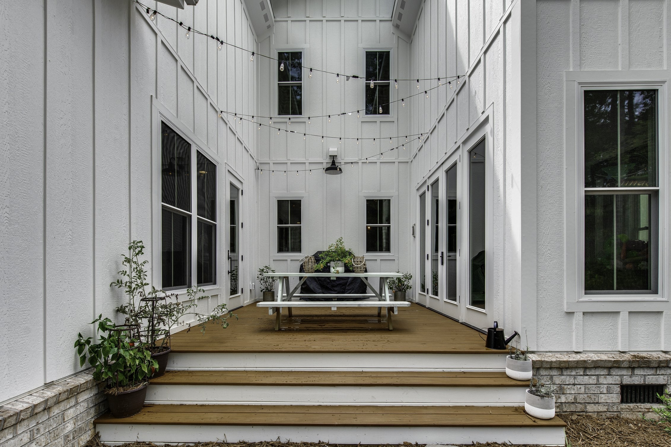 Outdoor living addition with wood deck, string lights, and modern farmhouse style exterior