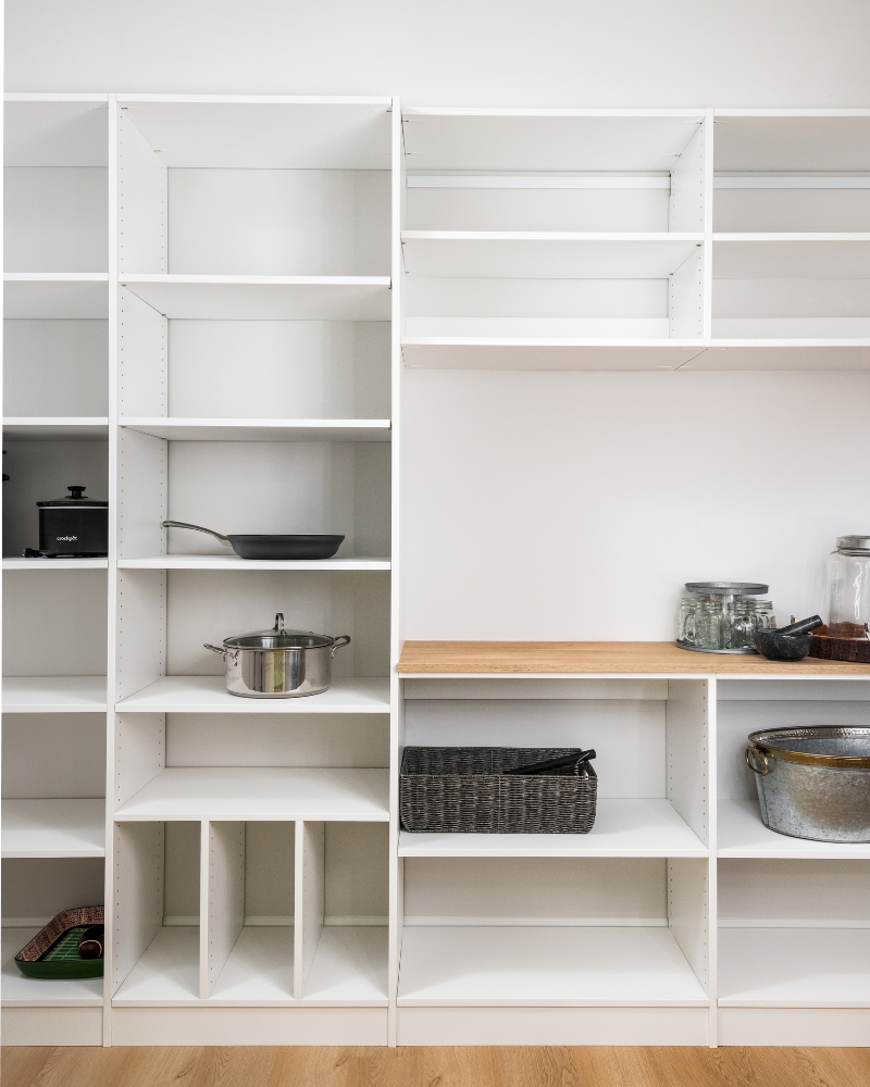 Walk-in basement pantry with floor-to-ceiling white adjustable shelving and a butcher block counter Walk-in basement pantry with floor-to-ceiling white adjustable shelving and a butcher block counter