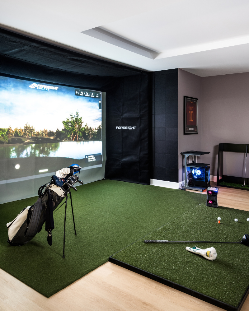 Golf simulator room with a recessed tray ceiling over the tee box, turf hitting mat, and impact screen Golf simulator room with a recessed tray ceiling over the tee box, turf hitting mat, and impact screen