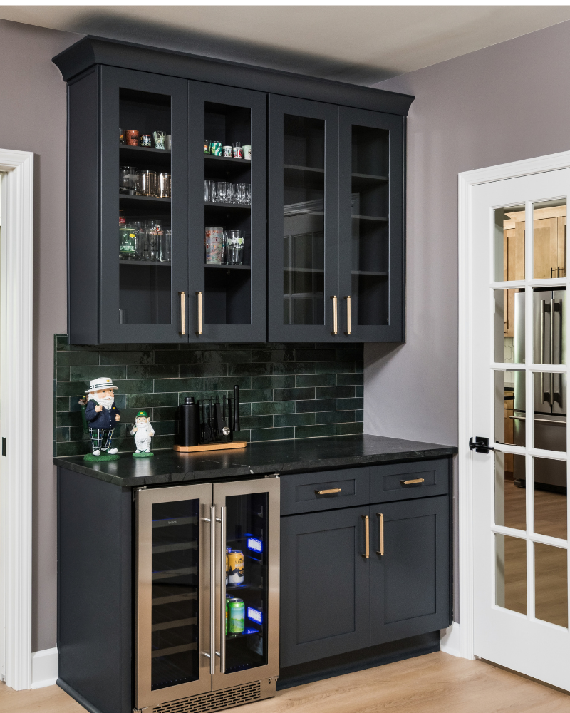 Golf room dry bar with charcoal shaker cabinets, glass-front uppers, deep green tile backsplash, brass pulls, and a dual-zone beverage refrigerator Golf room dry bar with charcoal shaker cabinets, glass-front uppers, deep green tile backsplash, brass pulls, and a dual-zone beverage refrigerator