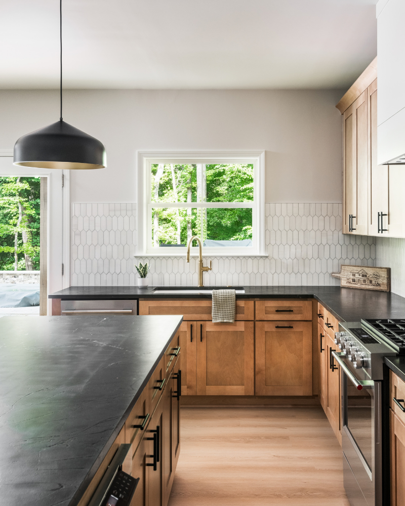 Basement kitchen in Indian Land, SC with light wood cabinets, black quartzite island, white picket tile, and a walkout door to the yard Basement kitchen in Indian Land, SC with light wood cabinets, black quartzite island, white picket tile, and a walkout door to the yard
