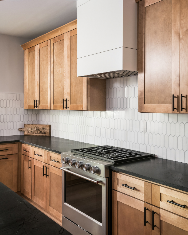 Basement kitchen in Indian Land, SC with light wood cabinets, black quartzite island, white picket tile, and a walkout door to the yard Basement kitchen in Indian Land, SC with light wood cabinets, black quartzite island, white picket tile, and a walkout door to the yard